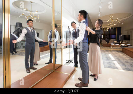 Fashion designers examining suit on customer Stock Photo