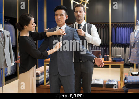 Fashion designers examining suit on customer Stock Photo