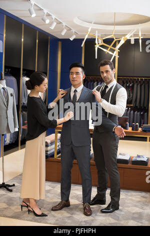 Fashion designers examining suit on customer Stock Photo