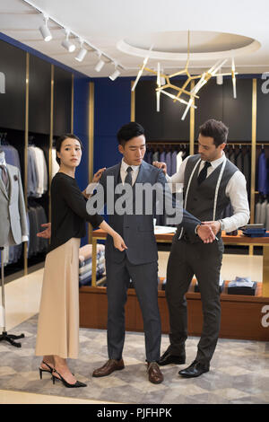 Fashion designers examining suit on customer Stock Photo