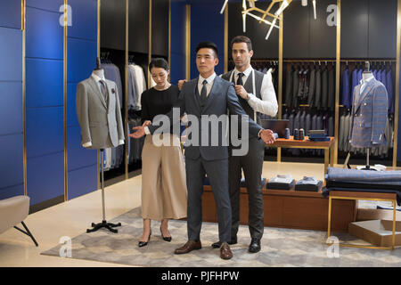 Fashion designers examining suit on customer Stock Photo