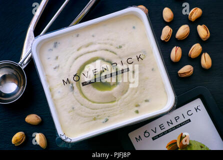 Tambov, Russian Federation - August 30, 2018 Movenpick pistachio ice cream in open box with spoon and pistachios. Black background. Stock Photo