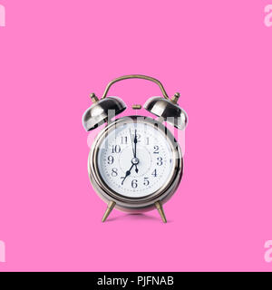 Retro classic alarm clock with bell, twin, showing seven o'clock standing on flat surface Isolated on pink Copy space Stock Photo