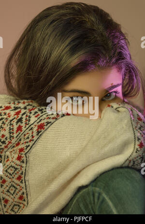 Beautiful girl looking at camera wearing warm clothes and her mouth covered. Stock Photo