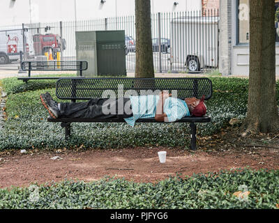 Homeless African-American or black man sleeping on a park bench in Montgomery Alabama, USA. Stock Photo