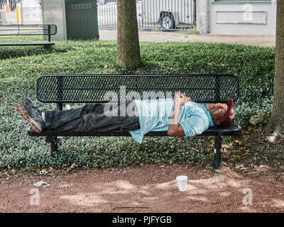 Homeless African-American or black man sleeping on a park bench in Montgomery Alabama, USA. Stock Photo