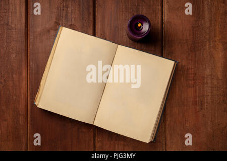 An overhead photo of an old book with a burning candle, shot from above on a dark rustic background Stock Photo