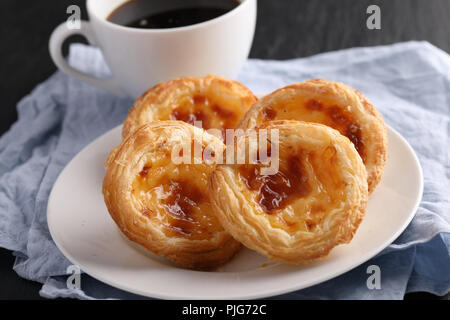 Portuguese egg tart pastry Pastel de nata on a plate with a cup of black coffee Stock Photo