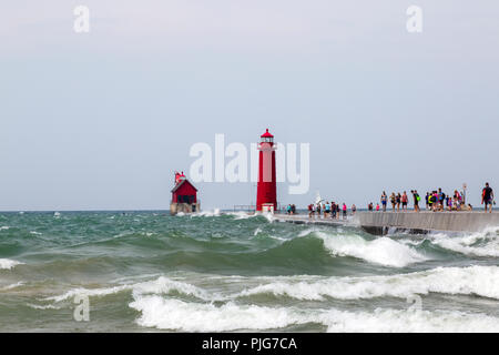 Tourists on a pier in south Haven Michigan on a day of rough waves on Lake Michigan. Grand Haven lighthouse. Stock Photo