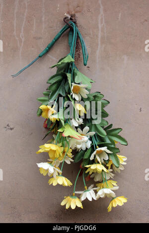 Plastic flowers bouquet hanging backwards in a Poblenou cemetery, Barcelona Stock Photo