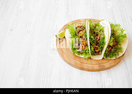 Shrimp tacos on round bamboo board on white wooden surface, low angle view. Mexican food. Copy space. Stock Photo