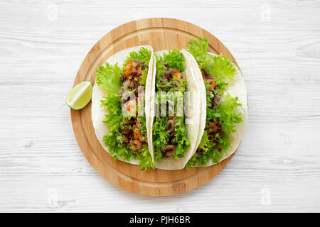 Shrimp tacos on round bamboo board on white wooden background, top view. Mexican food. Close-up. Flat lay, overhead, from above. Stock Photo