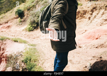 A hiker gives a hand to another person during hiking in a mountainous area. Support and teamwork. Stock Photo