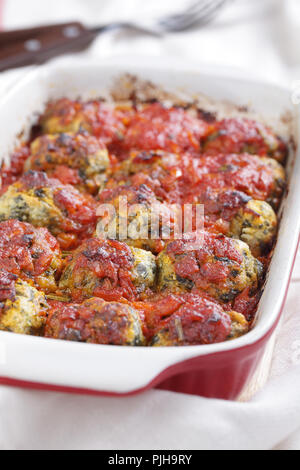 Baked spinach and ricotta dumplings under tomato sauce in the casserole Stock Photo