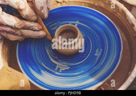 The man - Potter from the clay pitcher on a Potter's wheel. The old craft of pottery making Stock Photo