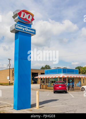 HICKORY, NC, USA-9/6/18: A 1950s-era Dairy Queen building, and more modern street sign. A young man cleans windows. Stock Photo