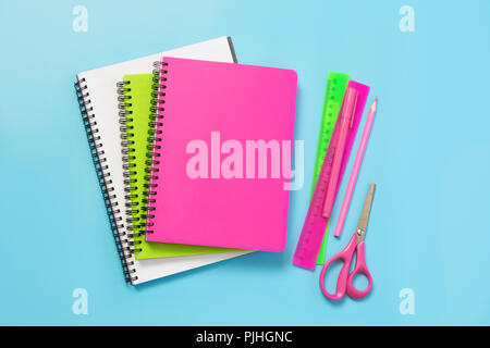 Colorful girlish school supplies, notebooks and pens on punchy blue. Top view, flat lay. Copy space. Stock Photo