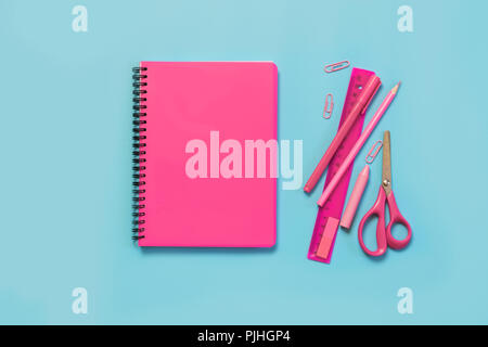 Pink girlish school supplies, notebooks and pens on punchy blue. Top view, flat lay. Copy space. Stock Photo