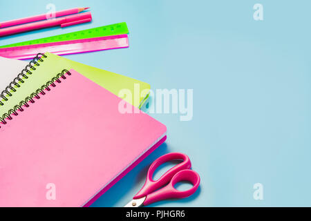 Colorful girlish school supplies, notebooks and pens on punchy blue. Top view, flat lay. Copy space. Stock Photo