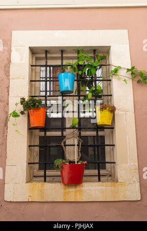 Window with colorful flower pots attached to iron bars. Old town, Crete, Greece Stock Photo