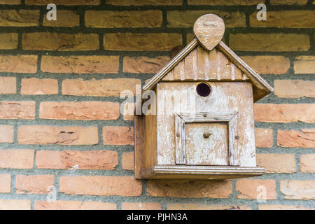 Hand crafted wooden bird house shelter for birds hanging on a brick wall Stock Photo