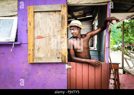 A young man standing at the door of his hut, Chatham Bay, Union, St-Vincent, Saint Vincent and the Grenadines, Lesser Antilles, West Indies, Windward Islands, Caribbean, Central America Stock Photo