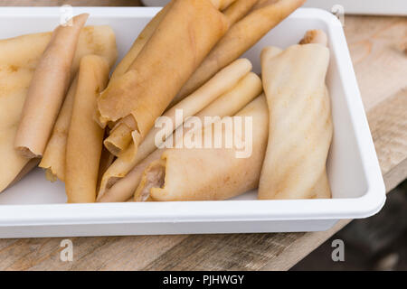 Close up of raw pork skins or pork rind which can be eaten as is or fried or roasted in pork fat (lard) as a snack. Stock Photo