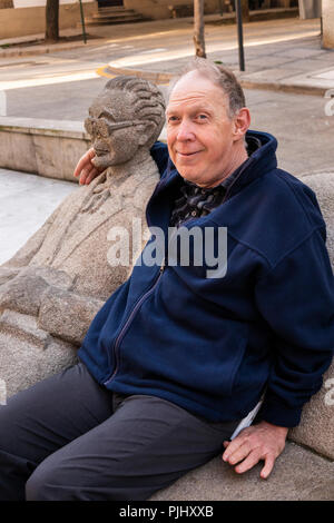 Spain, Galicia, A Coruna, Rua Pio XII, Prazo do Humor, disabled tourist sat next to sculpture on bench Stock Photo