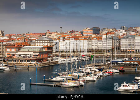 Spain, Galicia, A Coruna, harbour, boats moored in marina by glazed waterfront buildings Stock Photo