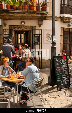 Spain, Jerez de La Frontera, Plaza de Abastos, customers sat at outside bar table in sunshine Stock Photo