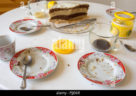 Dirty dishes on the table, homemade cake in the background Stock Photo