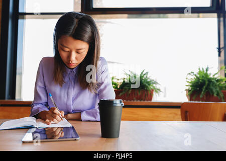 Young business woman making notes in cafe Stock Photo