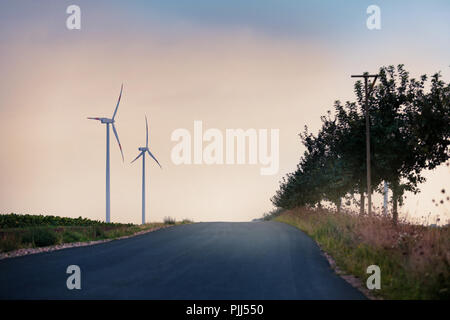 Street towards windmills under sunset. Stock Photo