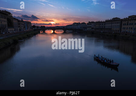 Ponte alla Carraia spans the River Arno in the city of Florence. Here the dramatic sky, reflection and stillness at sunset is captured. Stock Photo