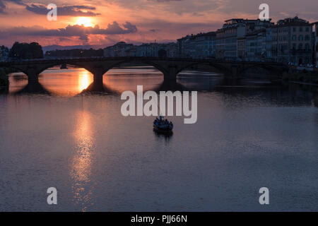 Ponte alla Carraia spans the River Arno in the city of Florence. Here the dramatic sky, reflection and stillness at sunset is captured. Stock Photo