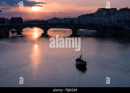 Ponte alla Carraia spans the River Arno in the city of Florence. Here the dramatic sky, reflection and stillness at sunset is captured. Stock Photo