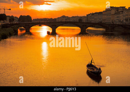 Ponte alla Carraia spans the River Arno in the city of Florence. Here the dramatic sky, reflection and stillness at sunset is captured. Stock Photo