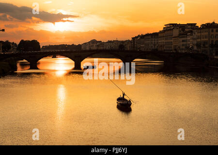 Ponte alla Carraia spans the River Arno in the city of Florence. Here the dramatic sky, reflection and stillness at sunset is captured. Stock Photo