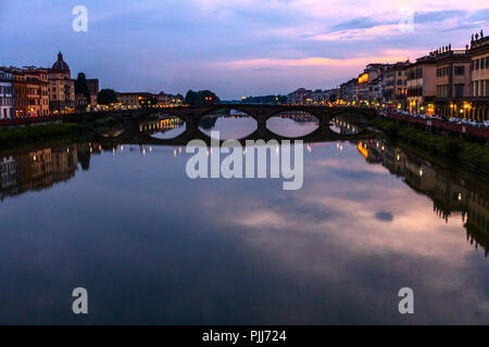 Ponte alla Carraia spans the River Arno in the city of Florence. Here the dramatic sky, reflection and stillness at sunset is captured. Stock Photo