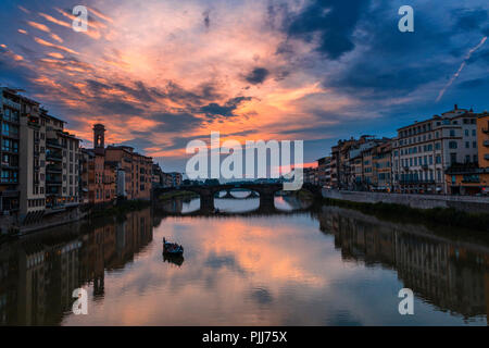 Ponte alla Carraia spans the River Arno in the city of Florence. Here the dramatic sky, reflection and stillness at sunset is captured. Stock Photo