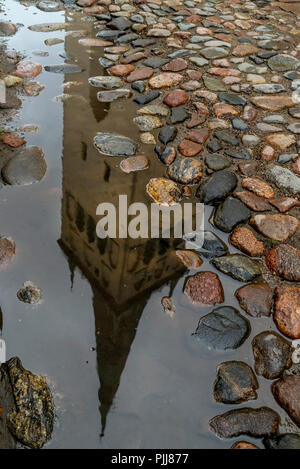 The bell tower of the Church of Sant Olav reflected in a puddle of water in the old town of Tallinn, Estonia Stock Photo