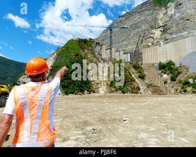 An Engineer signaling a crane during a visit to a hydropower construction site wearing safety helmet horizontal Stock Photo