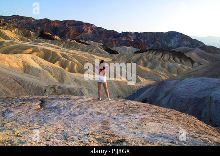 Colorful ridges landscape with standing attractive young woman open arms wide to feel free, traveler feels freedom and the power of natural beauty Stock Photo