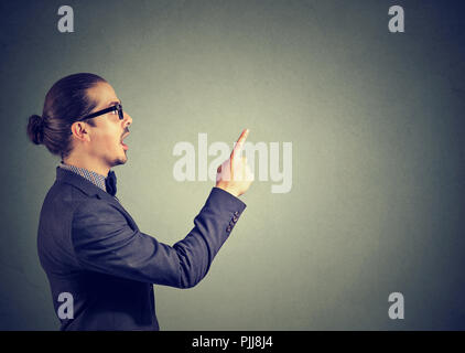 Side view of business man in holding finger up having bright idea on gray background Stock Photo