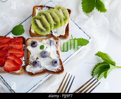 French toasts with cottage cheese, strawberries, kiwi  on a white wooden board, top view Stock Photo