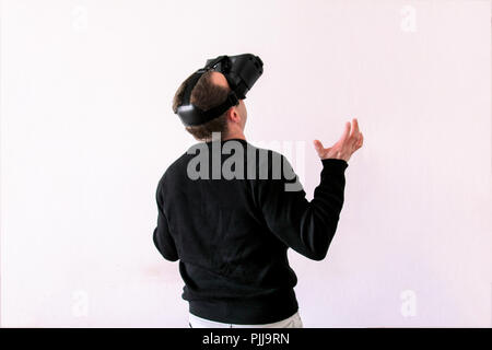 Man using a virtual glasses on white background. Young male business executive using virtual reality headset in office. Stock Photo