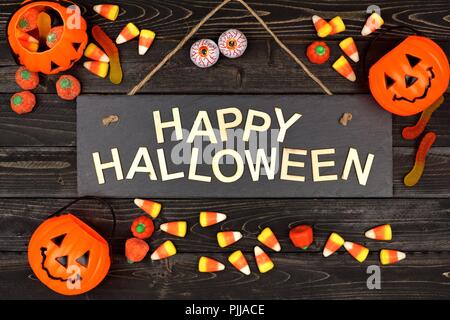 Happy Halloween black sign with wood letters and frame of candy on a black wood background Stock Photo