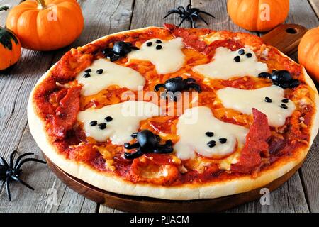 Halloween pizza with ghosts and spiders, close up on a rustic wood background Stock Photo