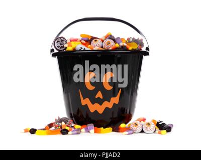 Black Halloween Jack o Lantern candy collector with scattered candy over a white background Stock Photo
