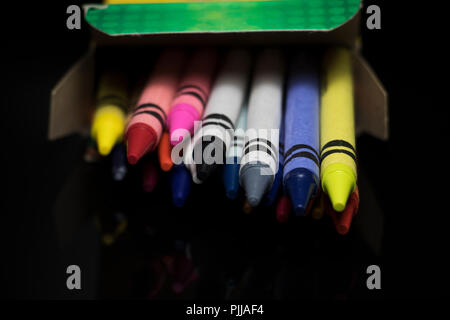 Crayons spilling out of a box. Kids coloring tools. Various colors of children's wax sticks for drawing. Stock Photo